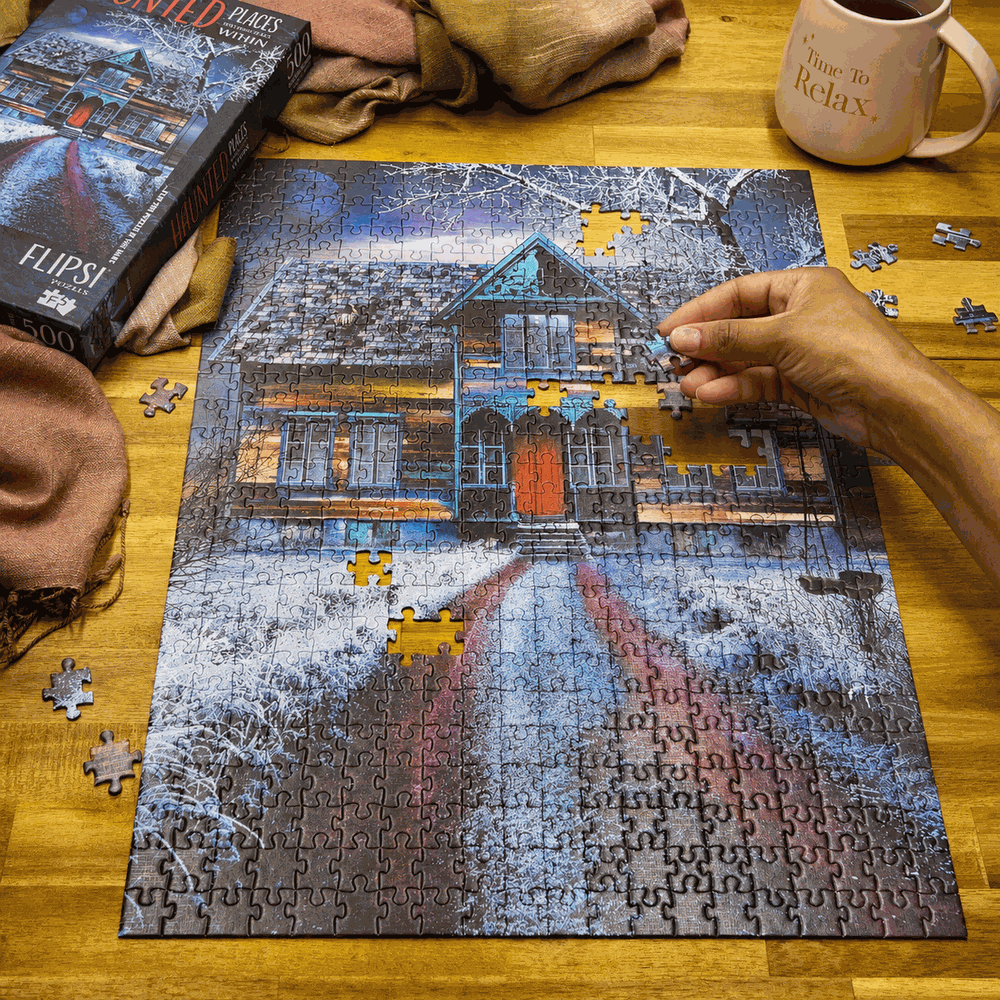 A Flipsi puzzle mid-build on a warm wooden table, a hand placing a piece