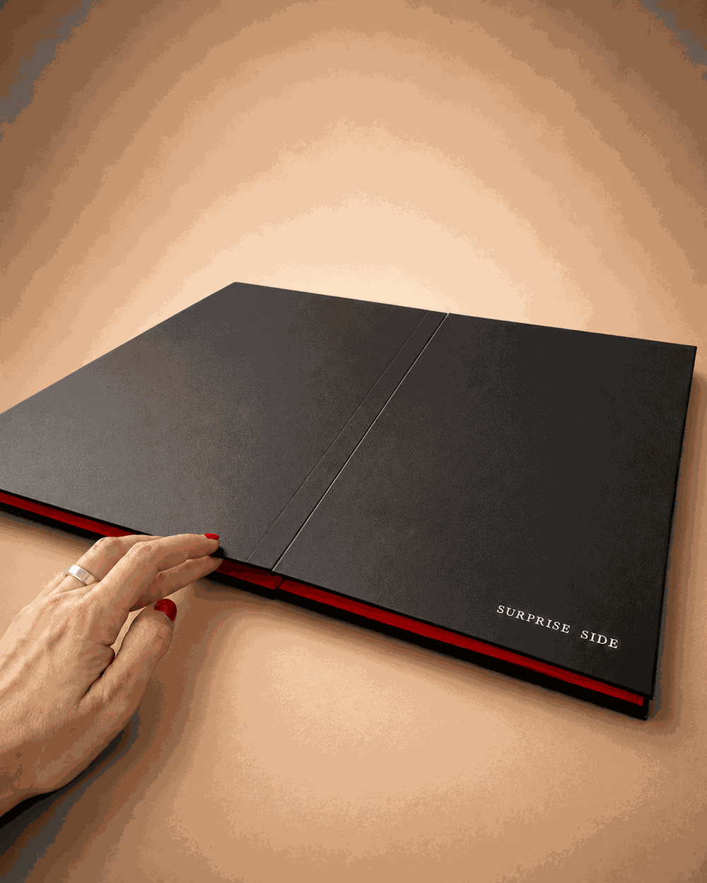 A hand resting on the closed Board, the surprise side still hidden
