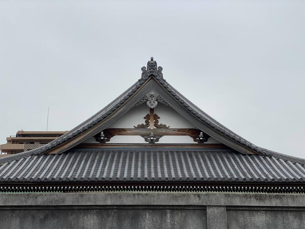 Source photograph: a tiled temple gable against a pale sky.